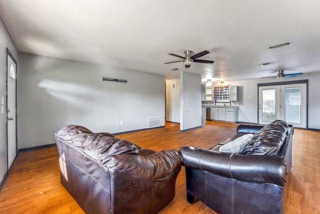 living room featuring hardwood / wood-style flooring, ceiling fan, and sink