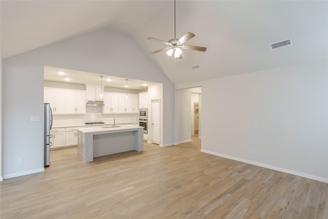 kitchen featuring stainless steel appliances, white cabinets, hanging light fixtures, an island with sink, and light wood-type flooring