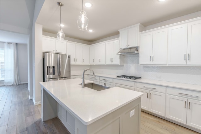 kitchen with stainless steel appliances, white cabinetry, sink, and light hardwood / wood-style flooring