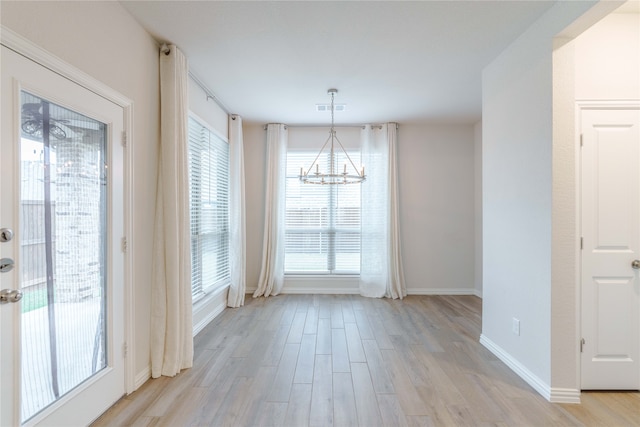 unfurnished dining area featuring light hardwood / wood-style floors, plenty of natural light, and an inviting chandelier