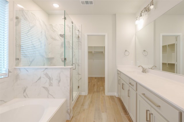 bathroom with hardwood / wood-style floors, vanity, and plus walk in shower