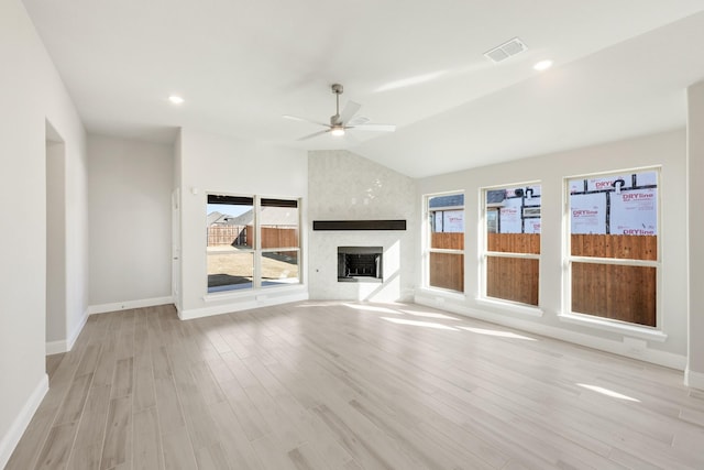 unfurnished living room featuring ceiling fan, a fireplace, vaulted ceiling, and light wood-type flooring