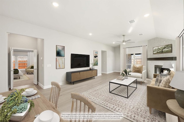 living room with a fireplace, light hardwood / wood-style floors, ceiling fan, and vaulted ceiling