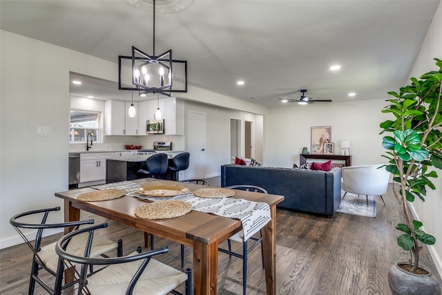 dining space featuring ceiling fan with notable chandelier, dark hardwood / wood-style flooring, and sink