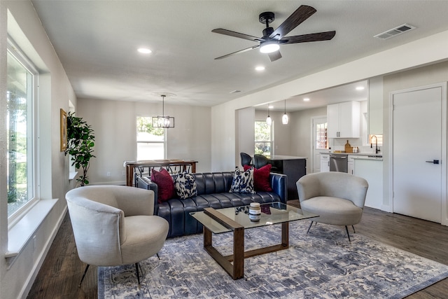 living room with sink, dark hardwood / wood-style flooring, a wealth of natural light, and ceiling fan with notable chandelier