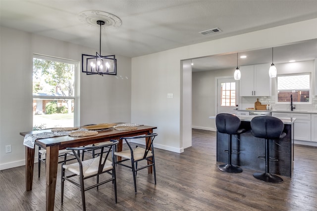 dining space with sink, dark hardwood / wood-style flooring, an inviting chandelier, and a healthy amount of sunlight