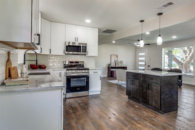 kitchen featuring stainless steel appliances, white cabinets, a center island, and sink