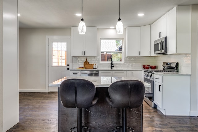 kitchen featuring stainless steel appliances, a kitchen island, white cabinets, and pendant lighting