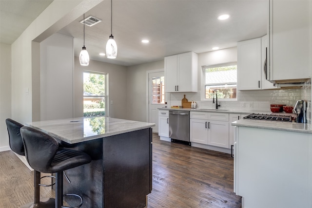 kitchen with a kitchen island, sink, white cabinetry, decorative light fixtures, and stainless steel dishwasher