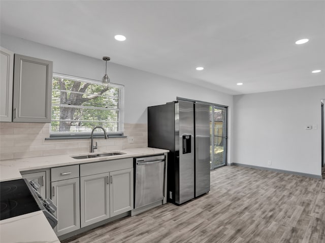 kitchen featuring light hardwood / wood-style floors, sink, gray cabinets, appliances with stainless steel finishes, and decorative light fixtures