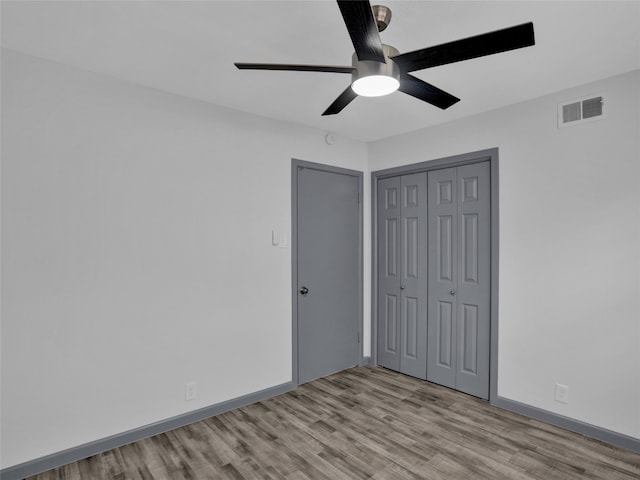 unfurnished bedroom featuring ceiling fan, a closet, and light hardwood / wood-style flooring