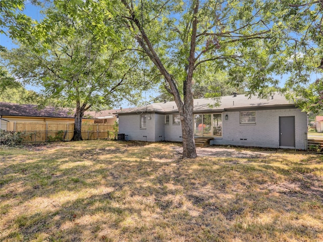 rear view of property with central AC unit and a yard