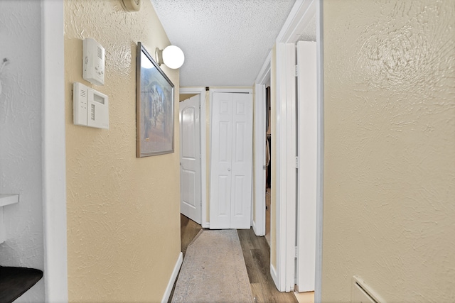 hallway with wood-type flooring and a textured ceiling