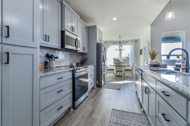 kitchen featuring pendant lighting, light hardwood / wood-style floors, appliances with stainless steel finishes, and sink