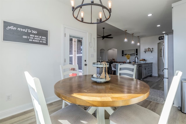 dining space featuring light wood-type flooring and ceiling fan with notable chandelier