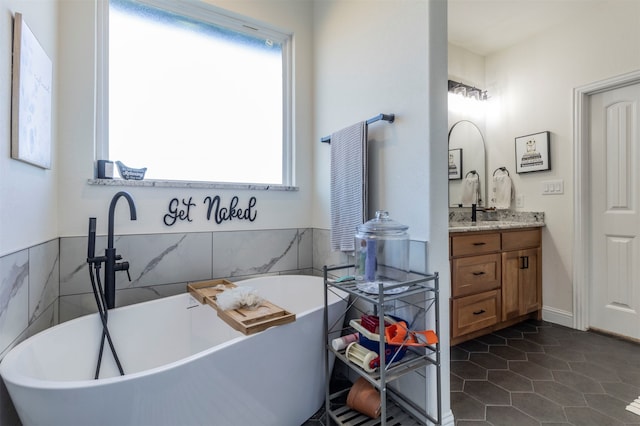 bathroom with a bathtub, vanity, tile patterned flooring, and tile walls