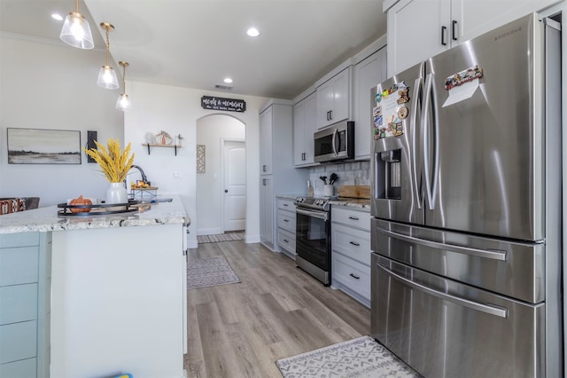 kitchen with white cabinetry, appliances with stainless steel finishes, decorative light fixtures, and light hardwood / wood-style flooring