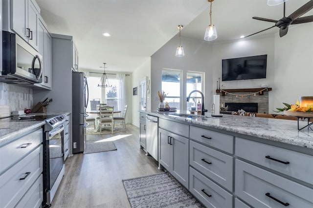 kitchen featuring a stone fireplace, stainless steel appliances, a healthy amount of sunlight, and sink