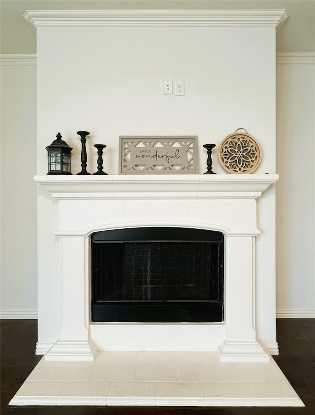 interior details with a tiled fireplace, hardwood / wood-style flooring, and crown molding