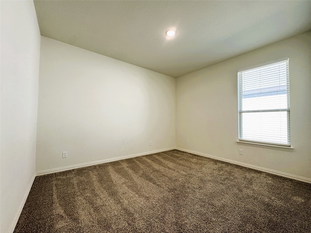 unfurnished room featuring dark carpet