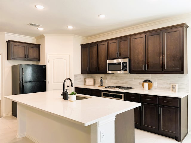 kitchen featuring a kitchen island with sink, sink, dark brown cabinets, and stainless steel appliances