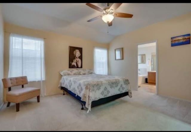 bedroom with ensuite bathroom, light carpet, ceiling fan, and vaulted ceiling