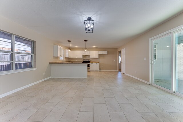 kitchen featuring light tile patterned flooring, kitchen peninsula, hanging light fixtures, white cabinets, and electric range