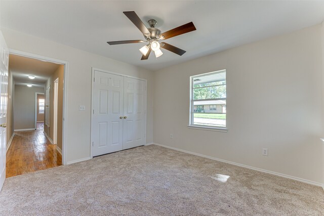 unfurnished bedroom featuring ceiling fan, a closet, and light colored carpet