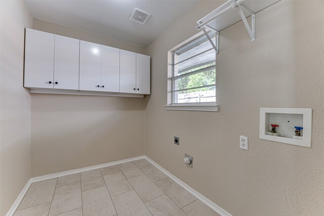 clothes washing area featuring light tile patterned flooring, hookup for an electric dryer, washer hookup, a textured ceiling, and cabinets