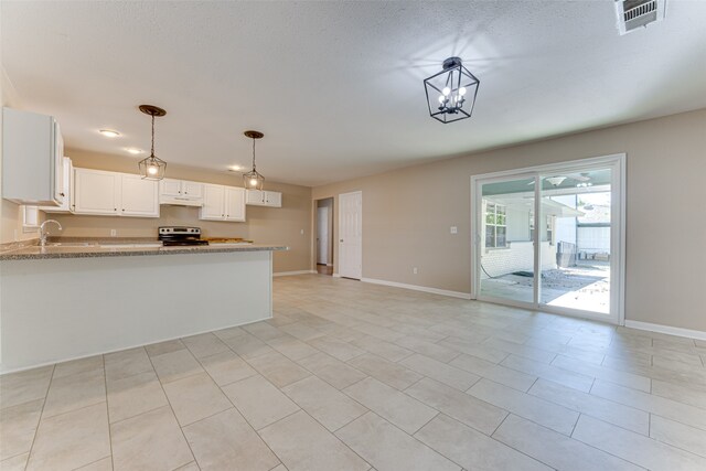 kitchen with sink, light stone counters, stainless steel range with electric cooktop, decorative light fixtures, and white cabinets