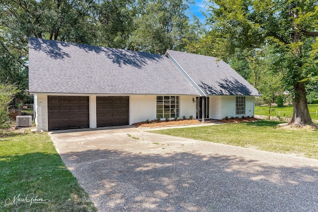 single story home featuring a garage, cooling unit, and a front yard