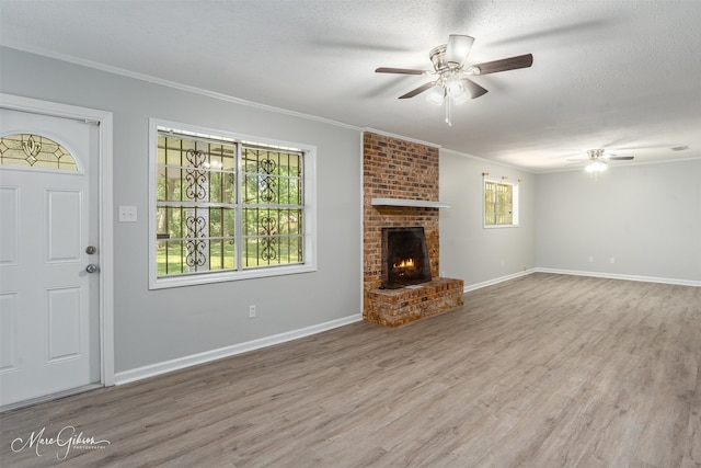 unfurnished living room with a brick fireplace, hardwood / wood-style floors, a wealth of natural light, and a textured ceiling