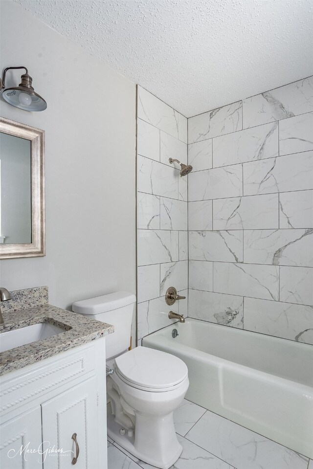 full bathroom with tiled shower / bath, a textured ceiling, toilet, and vanity