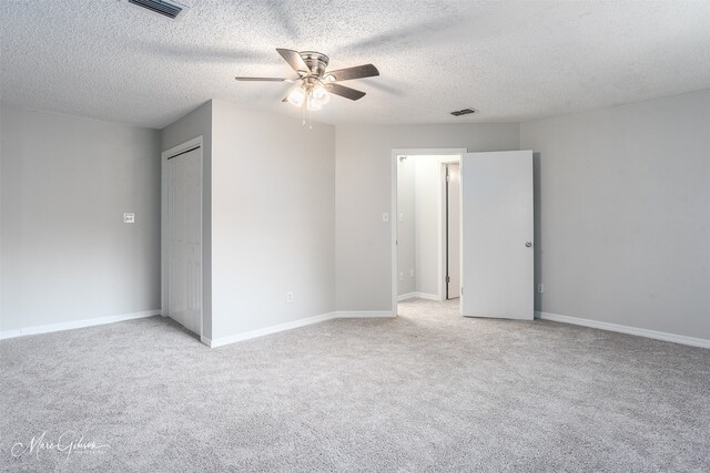 carpeted empty room featuring ceiling fan and a textured ceiling