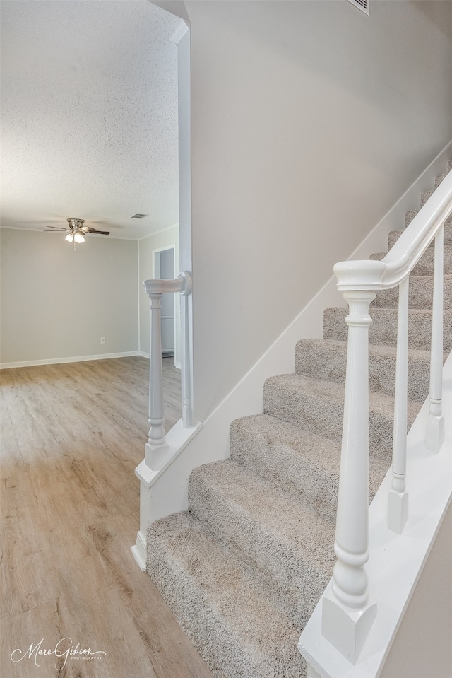 stairs featuring wood-type flooring and a textured ceiling