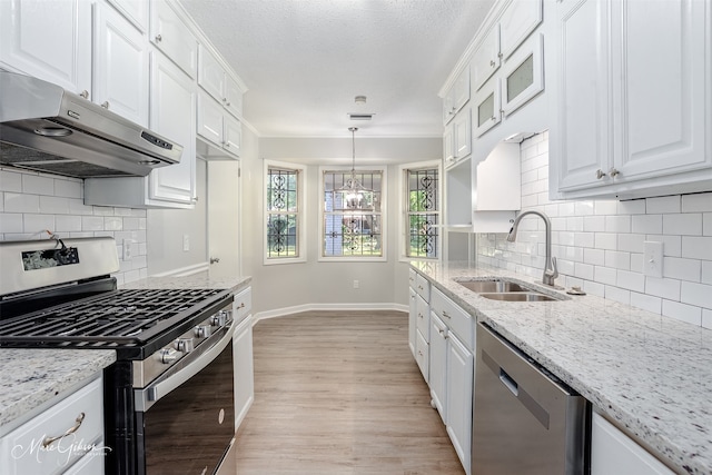 kitchen with stainless steel appliances, white cabinetry, pendant lighting, sink, and light hardwood / wood-style floors