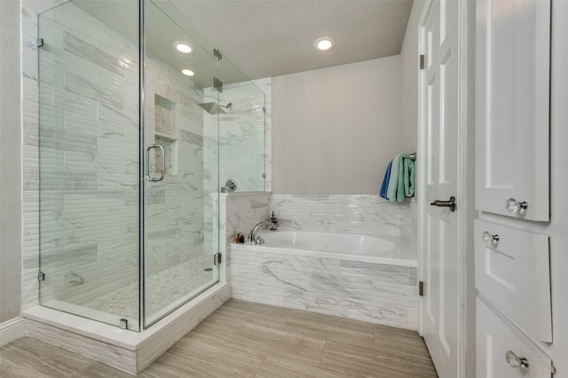 bathroom with a textured ceiling and separate shower and tub