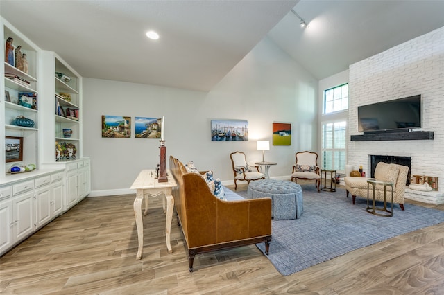 living room with a fireplace, light hardwood / wood-style floors, and lofted ceiling