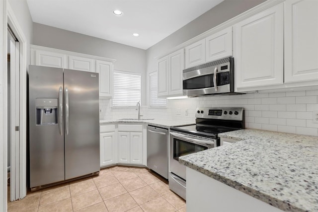 kitchen featuring white cabinets, light stone countertops, stainless steel appliances, and tasteful backsplash