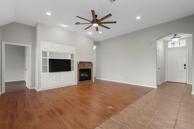 unfurnished living room featuring built in shelves, ceiling fan, light hardwood / wood-style flooring, and vaulted ceiling