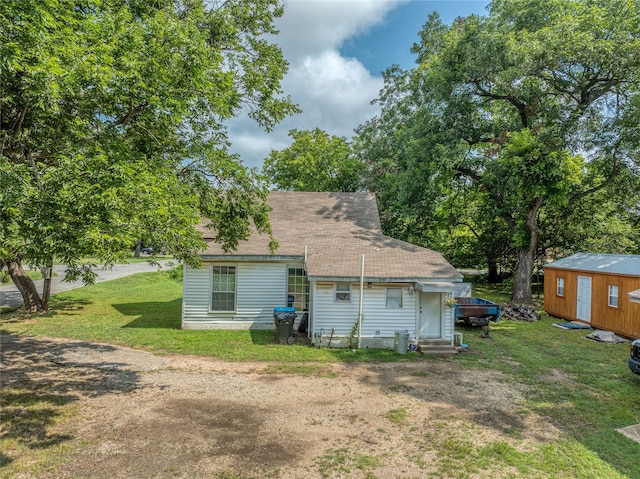 back of house with a shed and a yard