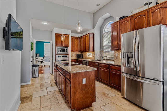 kitchen with light stone countertops, a center island, sink, stainless steel appliances, and pendant lighting