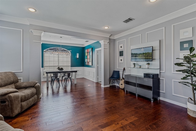 living room with decorative columns, crown molding, dark hardwood / wood-style flooring, and a notable chandelier