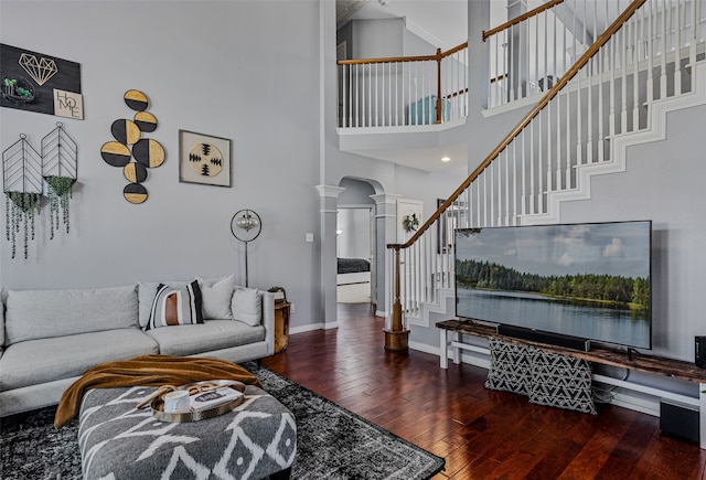 living room with decorative columns, dark hardwood / wood-style floors, and a high ceiling