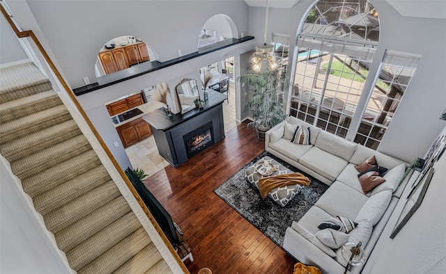 living room featuring a fireplace, dark wood-type flooring, and a high ceiling