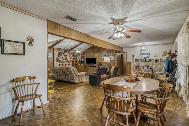 dining space with ceiling fan with notable chandelier, wood walls, a textured ceiling, ornamental molding, and dark parquet flooring