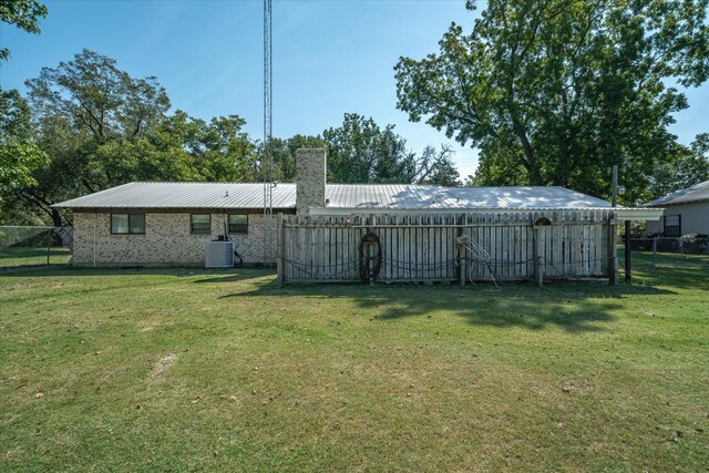 back of property featuring central AC and a yard