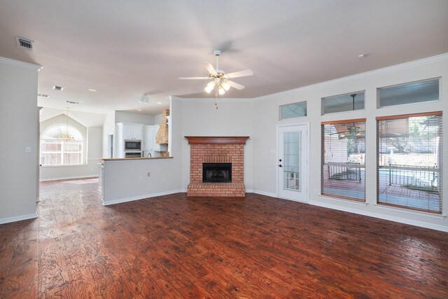 unfurnished living room featuring ceiling fan, ornamental molding, dark wood-type flooring, and a brick fireplace