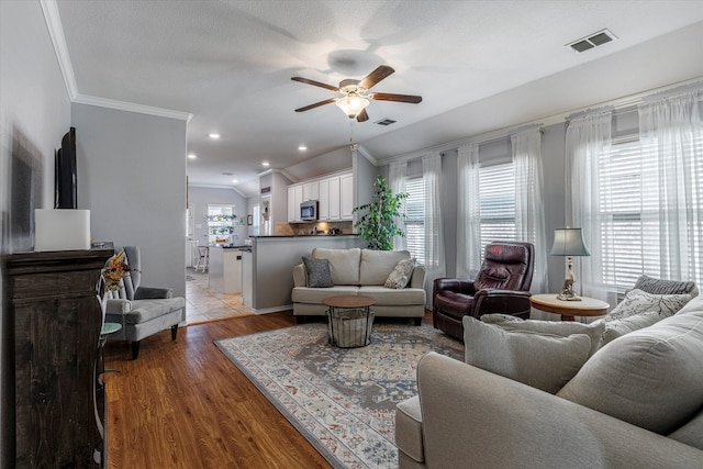 living room featuring light hardwood / wood-style floors, ceiling fan, plenty of natural light, and ornamental molding