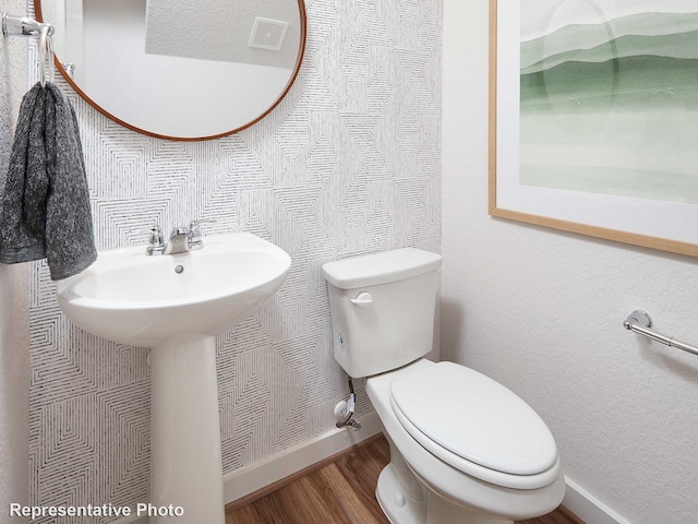 bathroom with a textured ceiling, hardwood / wood-style flooring, and toilet